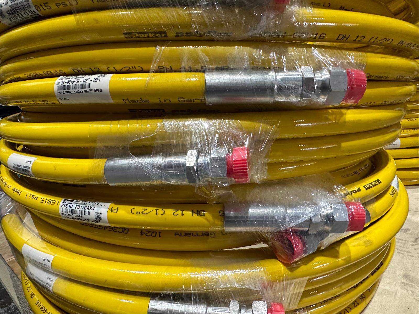 Yellow hose with metal fittings and red caps, wrapped in plastic, ready for industrial or hydraulic use.
