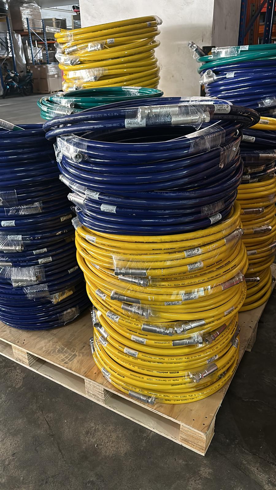 Coiled blue and yellow hoses stacked on a pallet, wrapped and labeled for storage or transport.