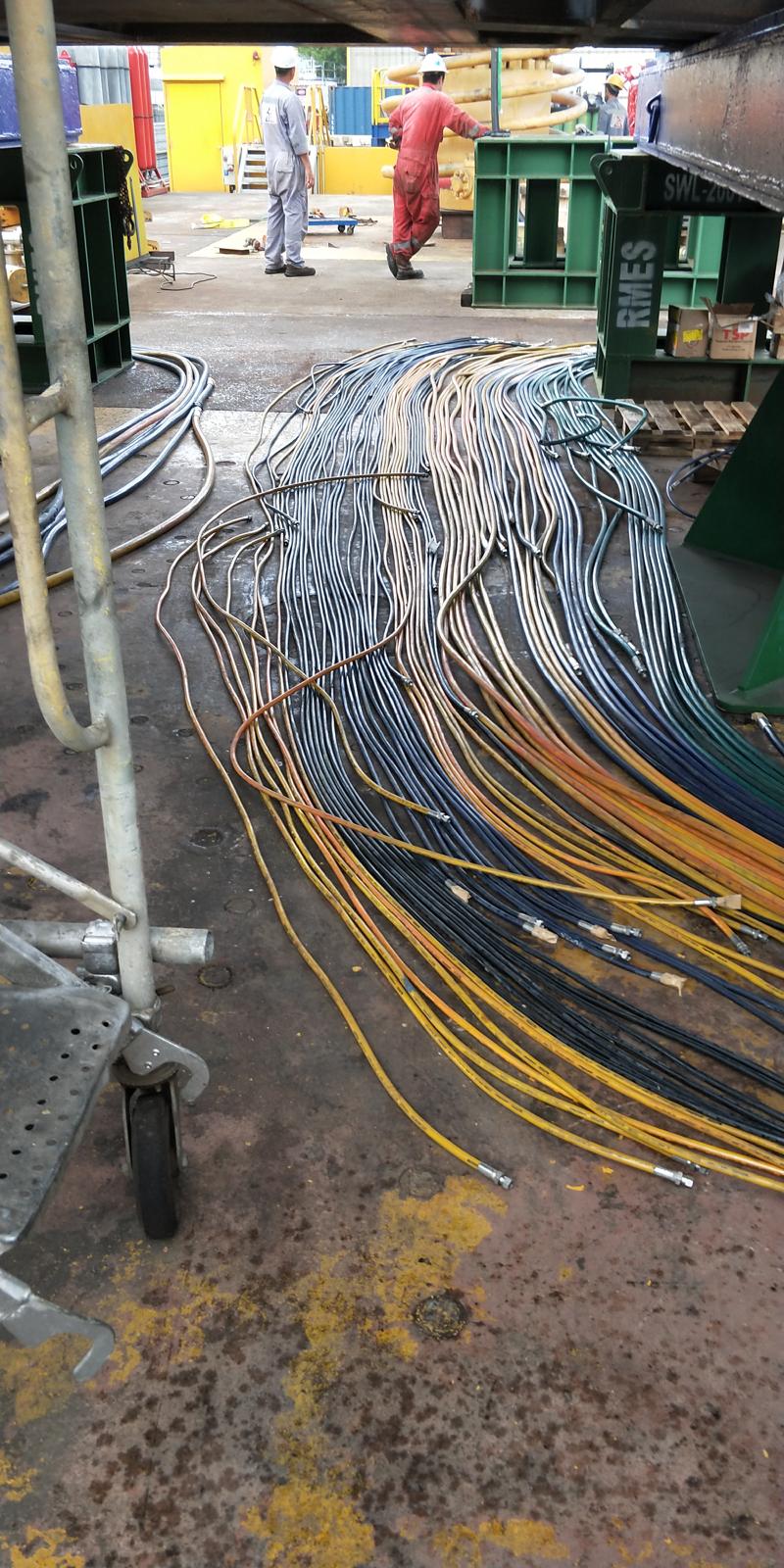 A large bundle of yellow and orange hoses tangled together, stored on a platform for industrial applications.